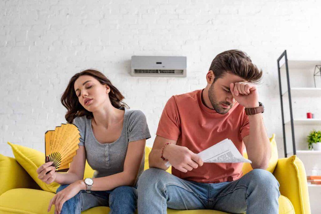 man-with-newspaper-and-woman-with-hand-fan-sitting