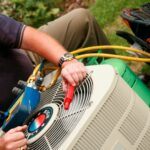 Service tech troubleshooting ice on copper AC line by checking the refrigerant level on a residential air conditioning unit.