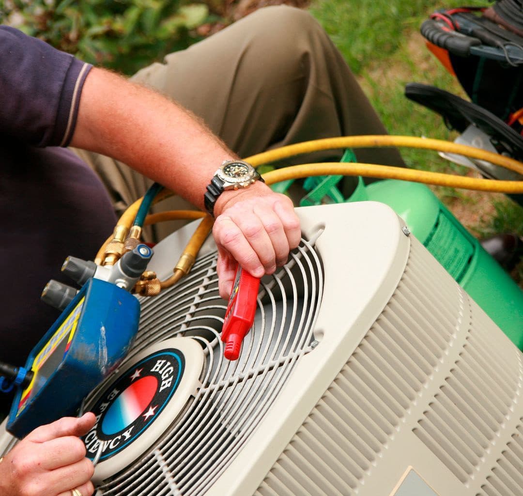 Service tech checking refrigerant level on a residential air conditioning unit.